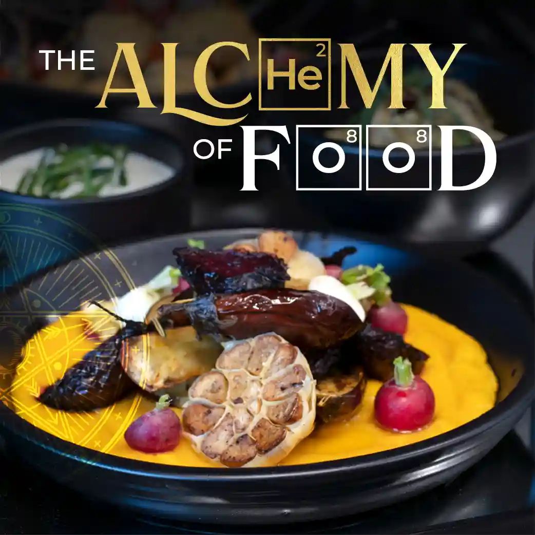 Tsebo Solutions Group | Tsebo_Catering_The_Alchemy_of_Food_A4_Issue_26_SEP_2026_WEB_500X500 A stylized graphic featuring the text "THE ALCHEMY OF FOOD," with "He" and "O" designed to resemble elements on the periodic table. The background is a close-up photograph of a plated gourmet meal containing a halved head of roasted garlic, eggplant, and radishes on a bright yellow puree in a black bowl. The bottom of the image includes the text "ISSUE 26 | SEPTEMBER 2026" alongside white Tsebo logos.